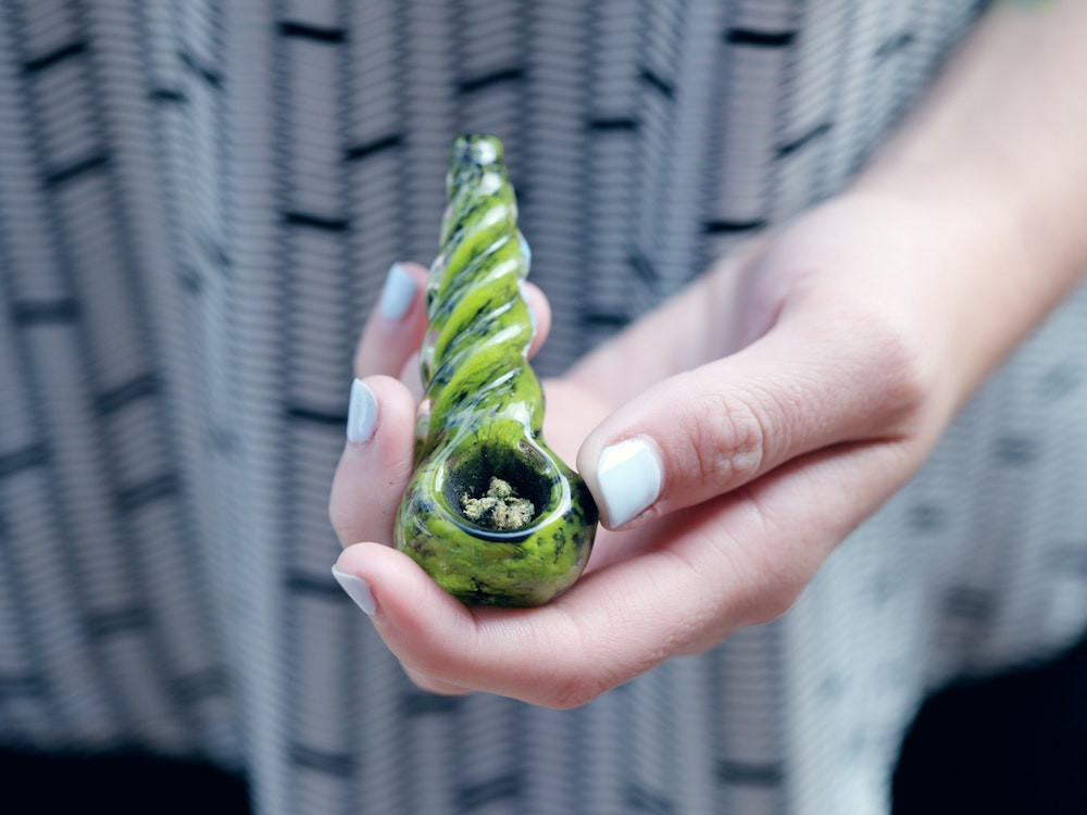 Green cannabis pipe in woman's hand